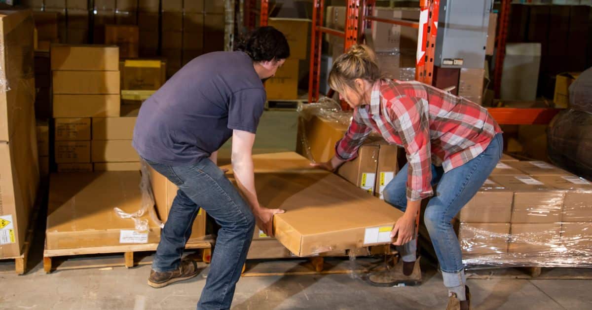 Man and woman working together to lift a heavy box onto a pallet